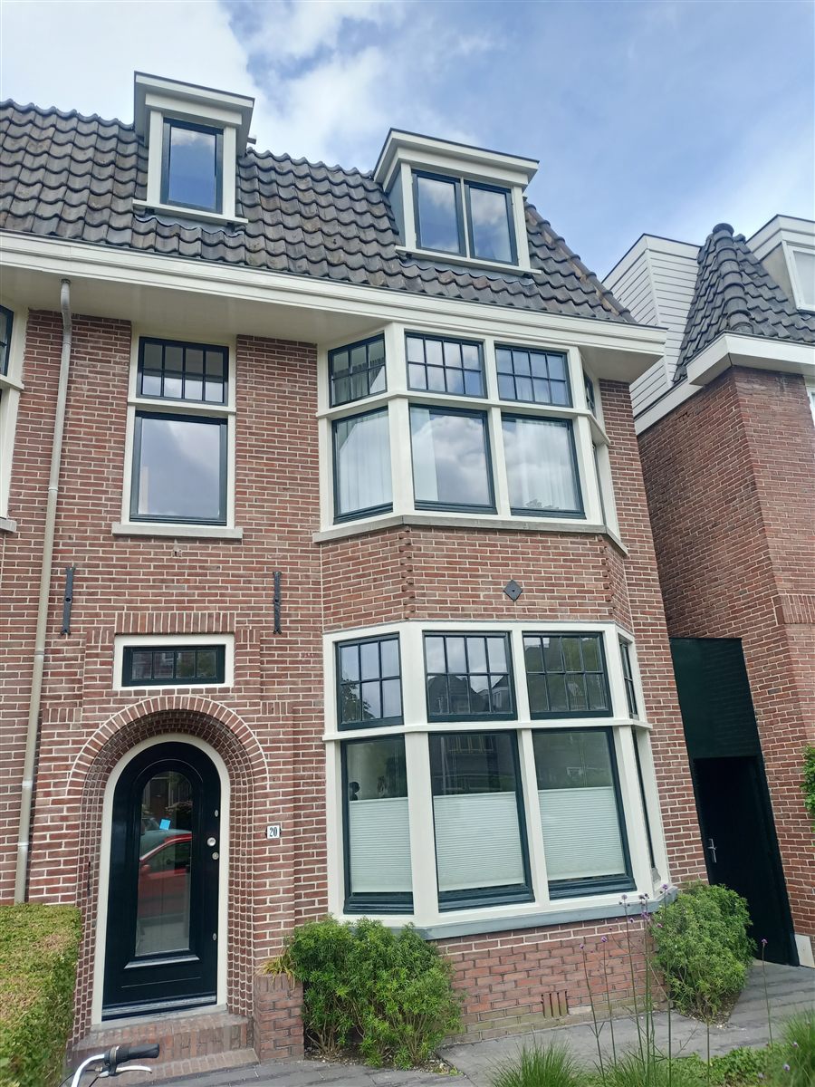 Herenhuis met bakstenen gevel en wit geschilderde kozijnen en erker