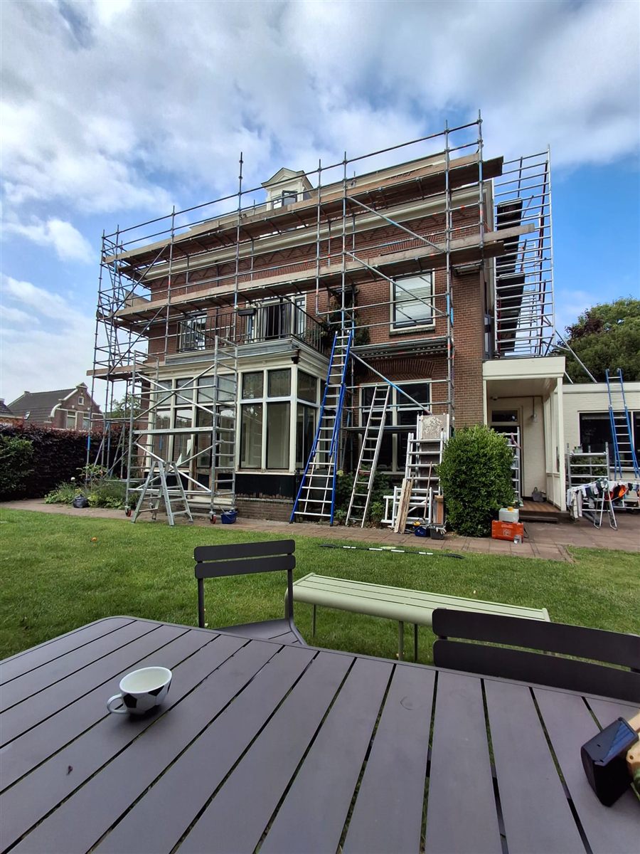 Buitenschilderwerk in uitvoering op groot pand met steiger