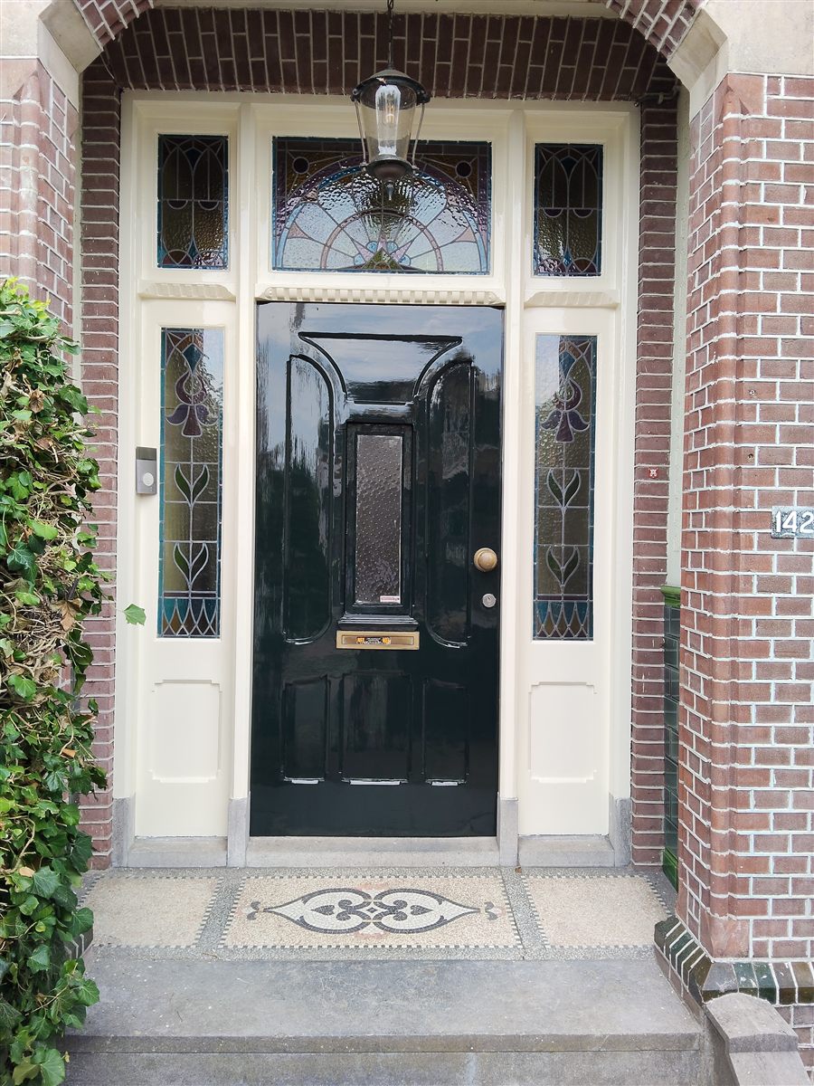 Gerenoveerde zwart geschilderde voordeur met glas-in-lood na behandeling