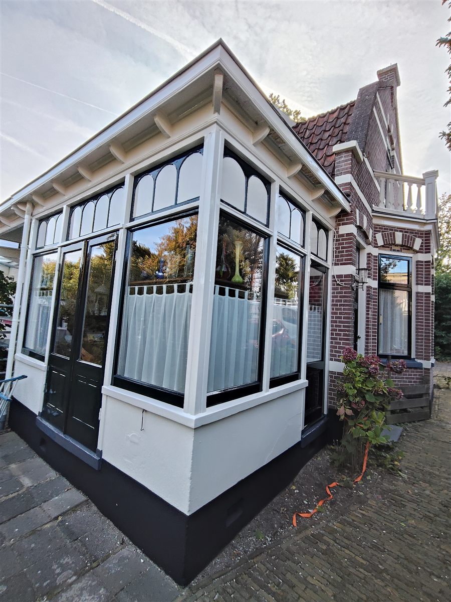 Wit geschilderde serre met zwarte details en glas-in-lood kozijnen